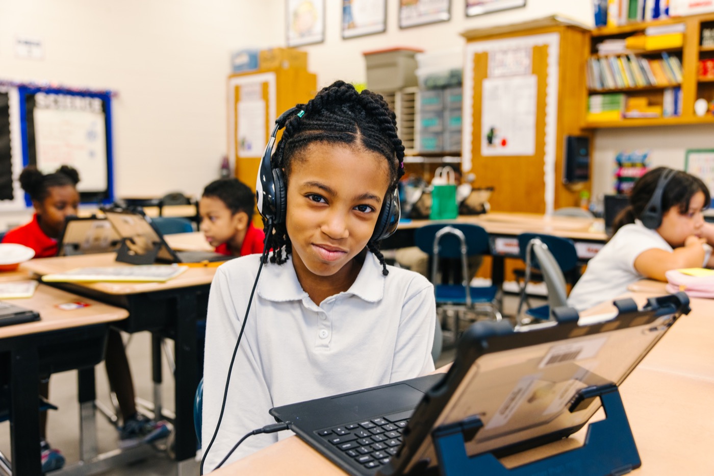 A student wearing headphones while using a classroom device
